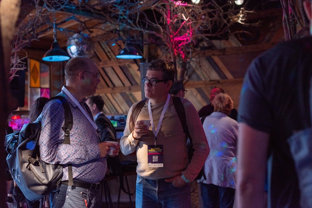 Two people talking in small groups at a networking event, holding coffee cups